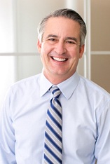 older man wearing a tie and smiling