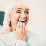 a patient checking her new dentures with a mirror 