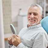 patient smiling after paying the cost of his dentures