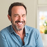 older man smiling while inside home 