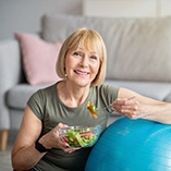 older woman smiling while eating salad 