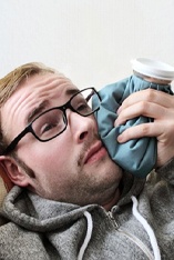 man lying down and holding ice pack to his cheek