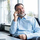 Older man with dental implants in Park Slope using a phone