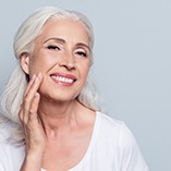 Smiling woman with dental implants in Park Slope touching her face