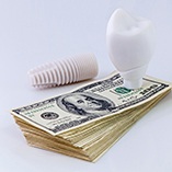 Model of a dental implant in Park Slope resting on money