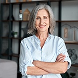 Woman with grey hair smiling with arms crossed
