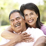 Couple smiling together outside with green background