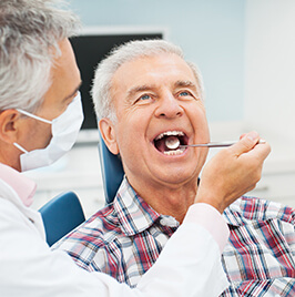 dentist checking man's teeth with dental mirror