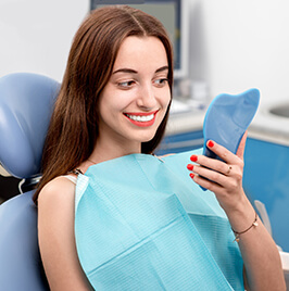 woman looking at her white teeth in the mirror